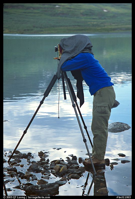 Large format photographer under dark cloth on the shores of Turquoise Lake. Lake Clark National Park, Alaska