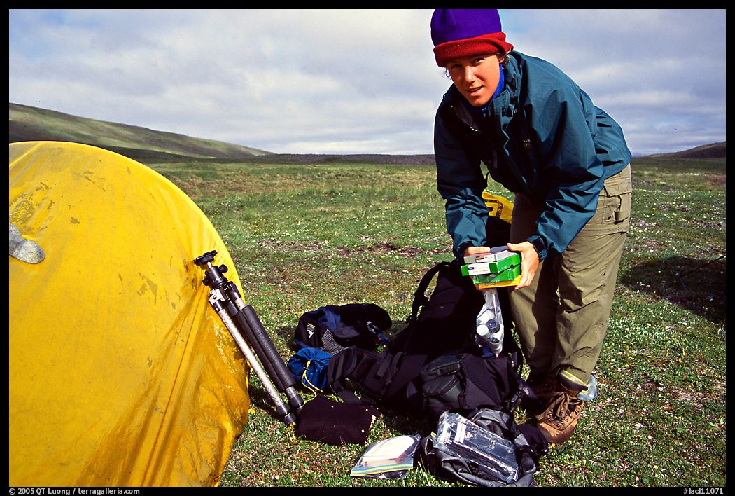 Photographer unpacking boxes of film from backpack. Lake Clark National Park, Alaska
