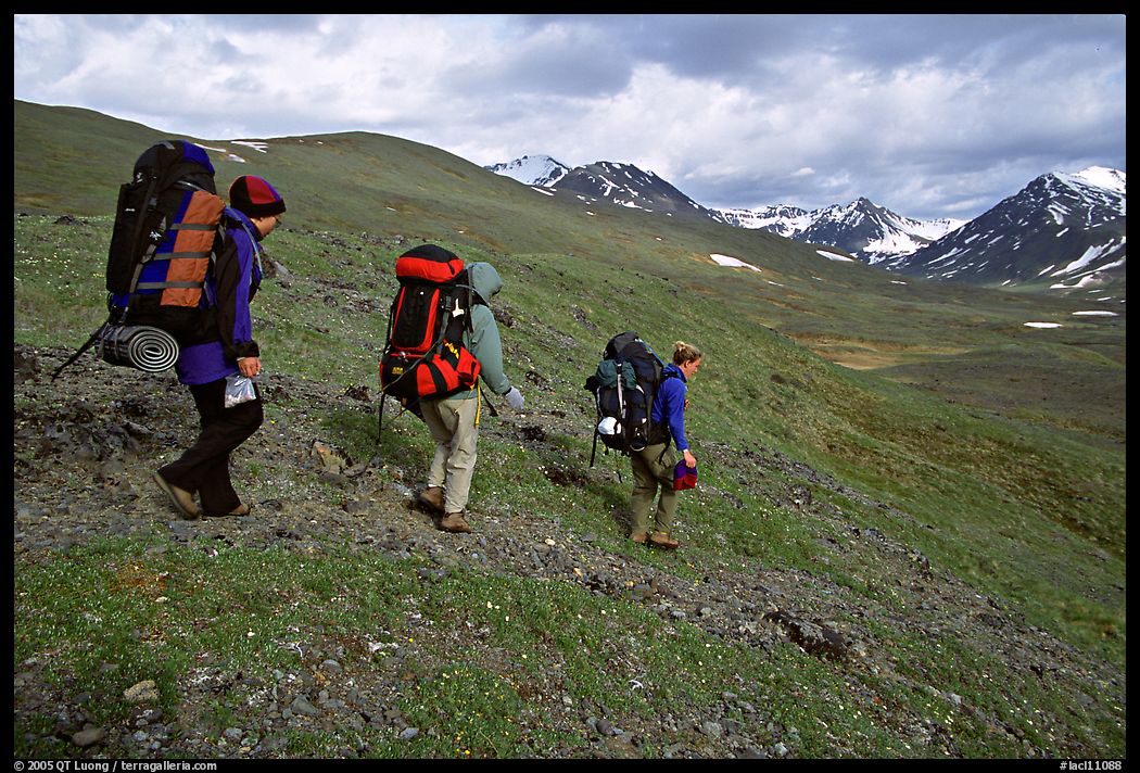 Backpackers with big packs going down a slope. Lake Clark National Park, Alaska
