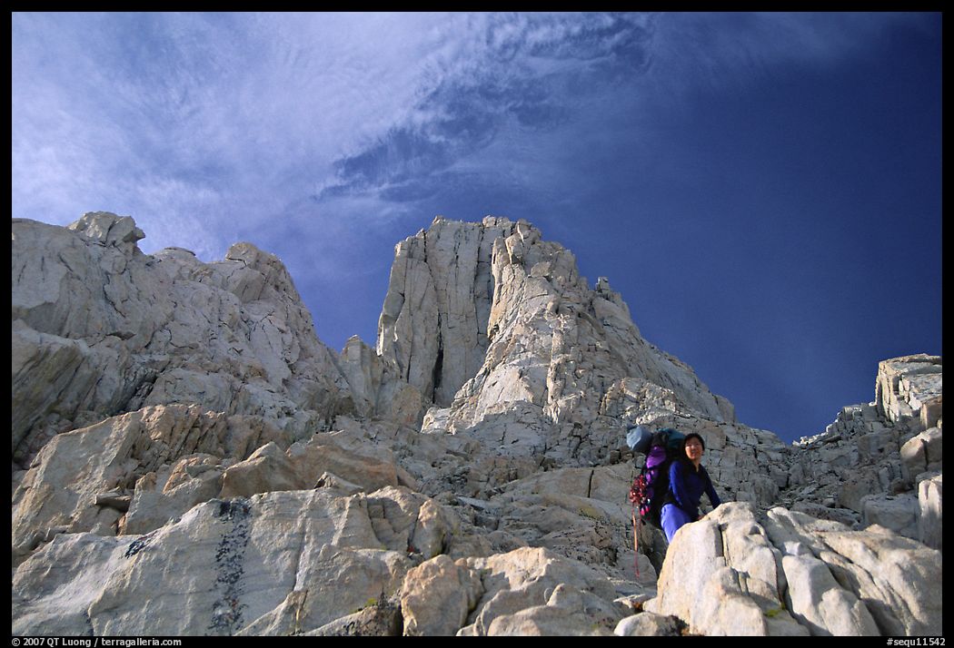 Looking up to woman scrambling on rocks on the East face of Mt Whitney. Sequoia National Park, California