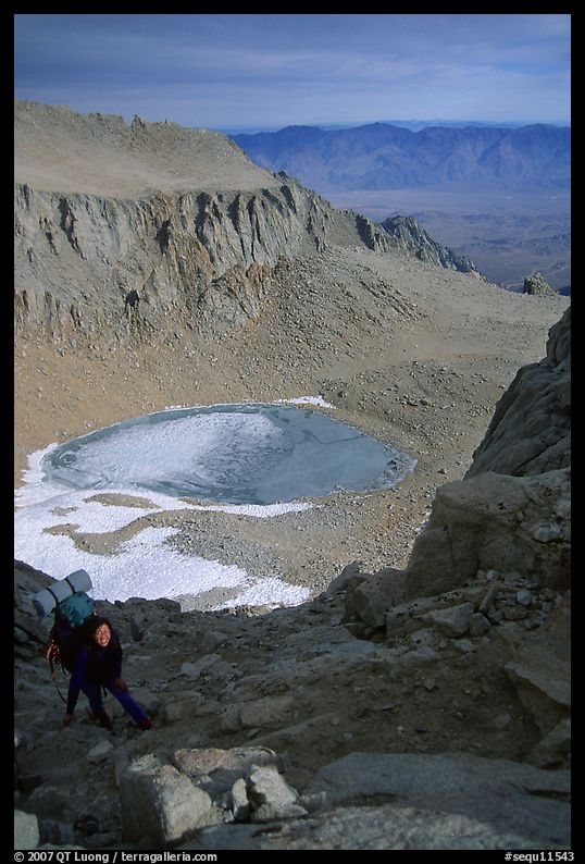 Woman on steep slope above frozen Iceberg Lake. Sequoia National Park, California