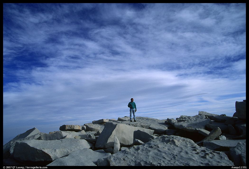 Hiker standing on flat rocks on top of Mt Whitney summit. Sequoia National Park, California