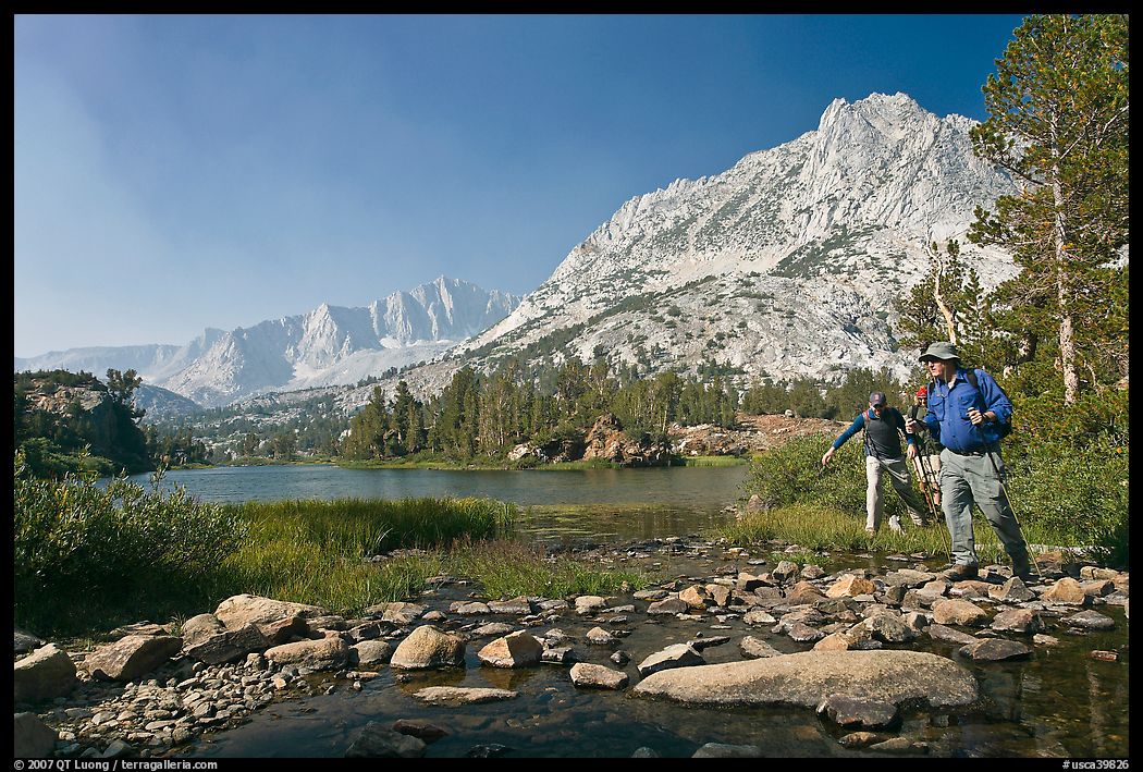 Hikers crossing stream on rocks at Long Lake, John Muir Wilderness. Kings Canyon National Park, California