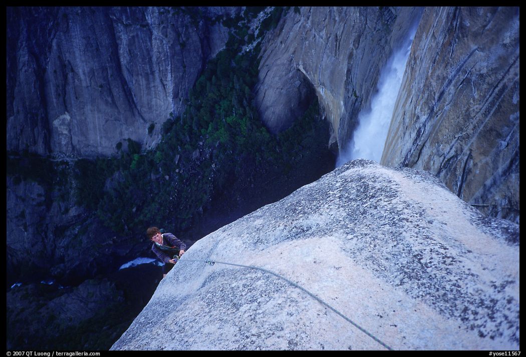 Climber near the top of Lost Arrow spire with Yosemite Falls behind. Yosemite National Park, California