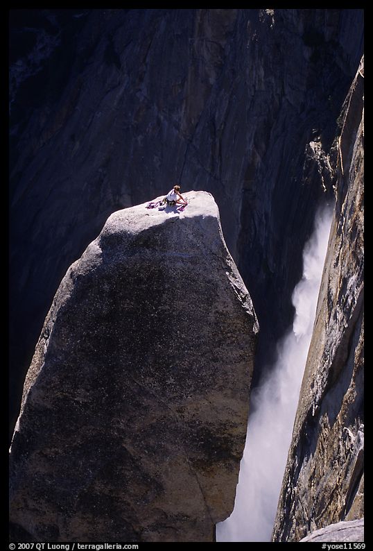 Climber resting on top of Lost Arrow spire with Yosemite Falls behind. Yosemite National Park, California