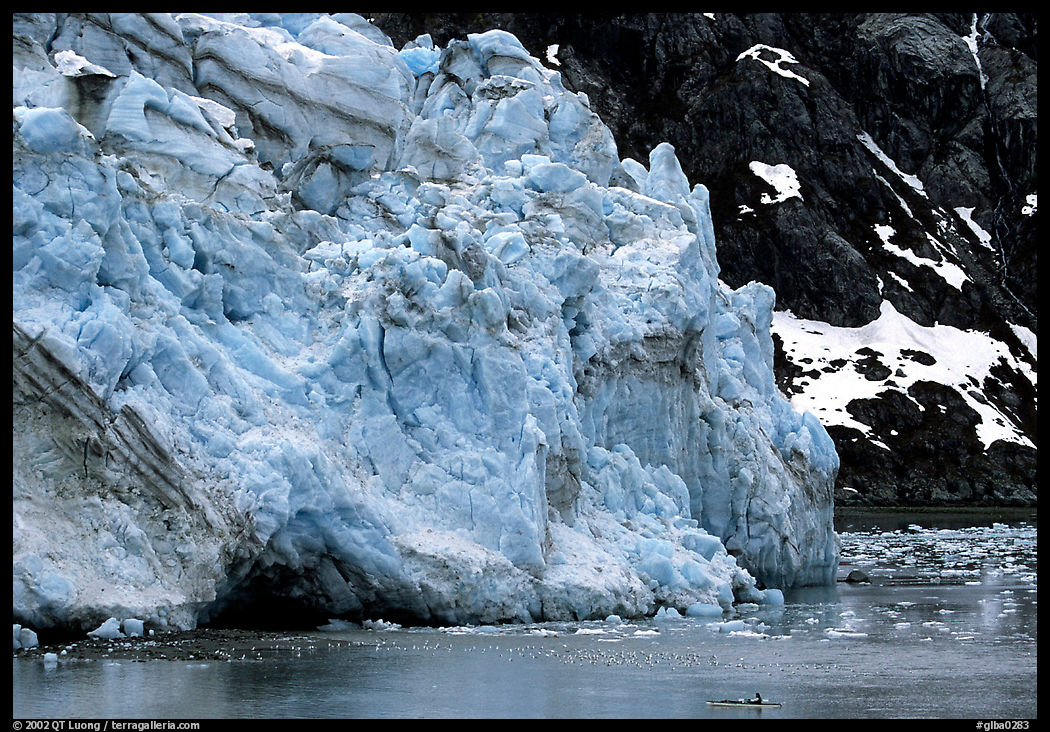 Kayaker dwarfed by Lamplugh glacier. Glacier Bay National Park, Alaska, USA.