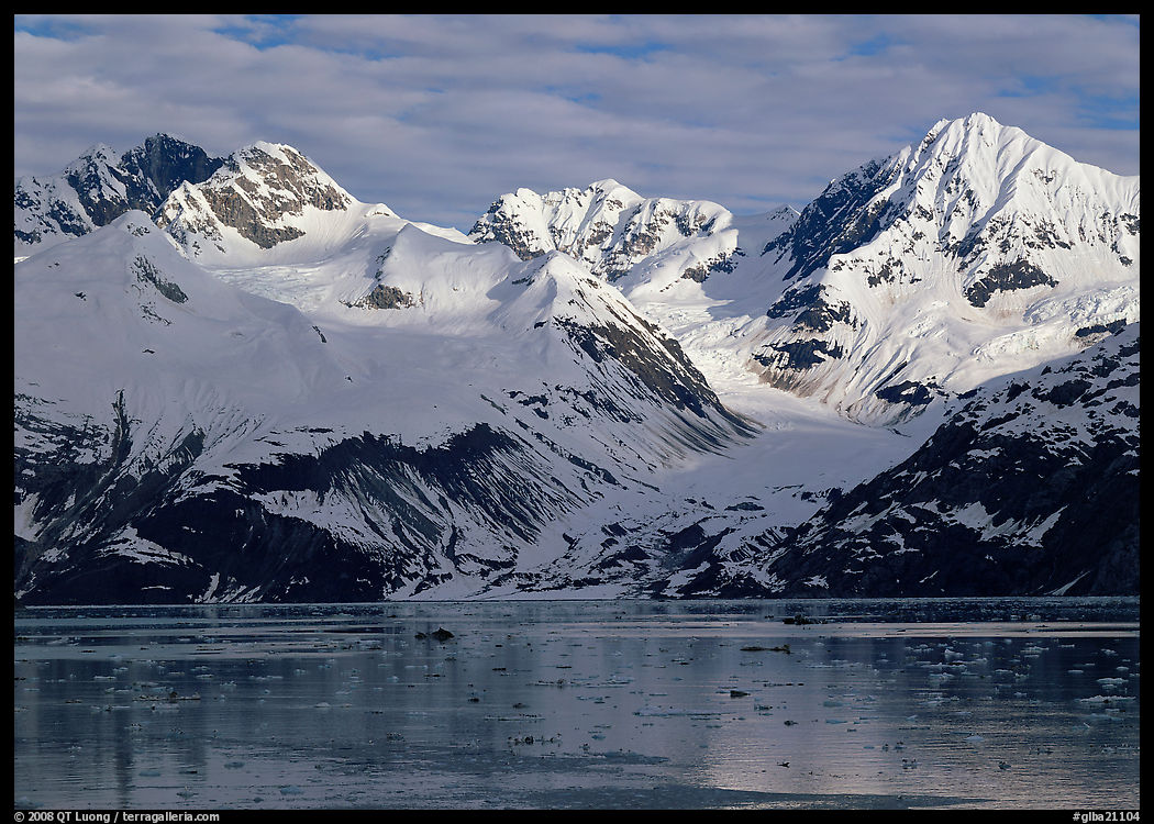 Coastal mountains with glacier dropping into icy fjord. Glacier Bay National Park, Alaska, USA.