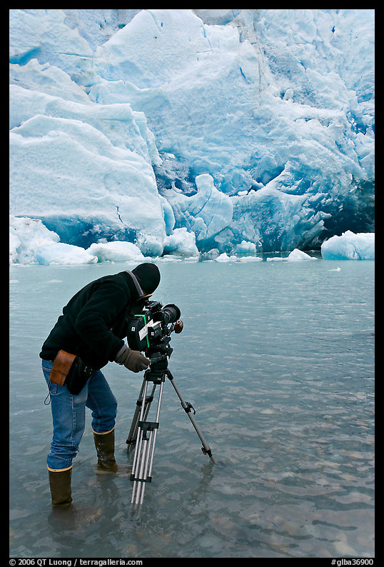 Cameraman standing in water with camera and tripod filming Reid Glacier. Glacier Bay National Park, Alaska, USA.