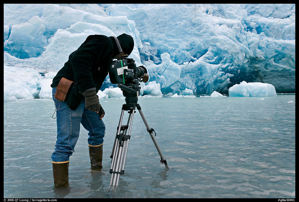 Cameraman standing in water at the base of Reid Glacier. Glacier Bay National Park, Alaska, USA.