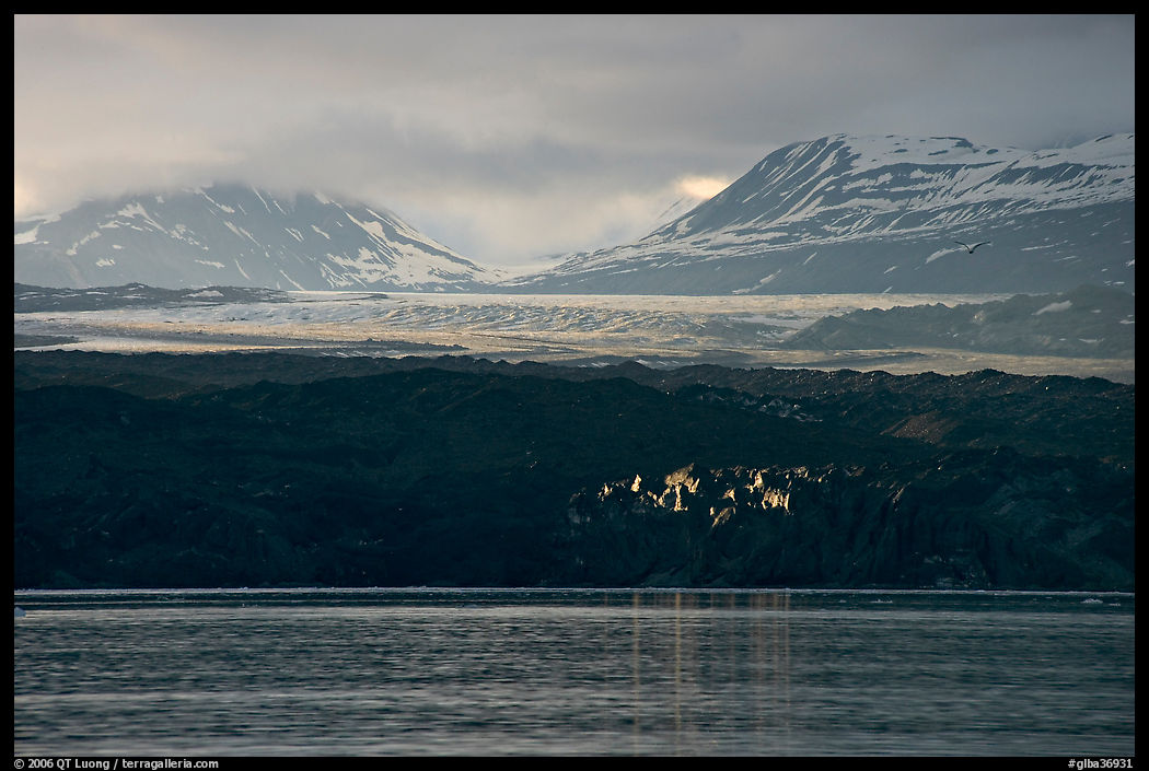 Last sunrays catched by the moraine-covered face of Grand Pacific Glacier. Glacier Bay National Park, Alaska, USA.