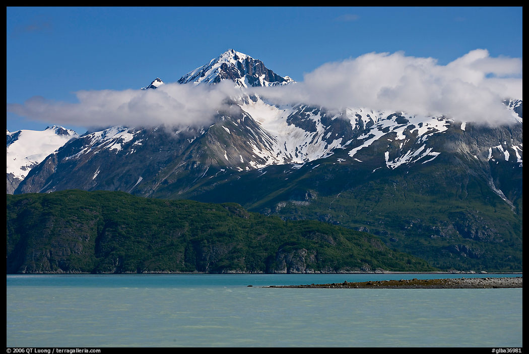 Snowy peaks and clouds raising above turquoise waters in sunny weather. Glacier Bay National Park, Alaska, USA.
