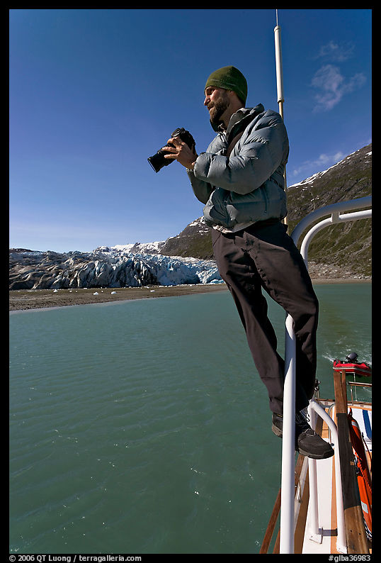 Photographer perched on boat in Reid Inlet. Glacier Bay National Park, Alaska, USA.