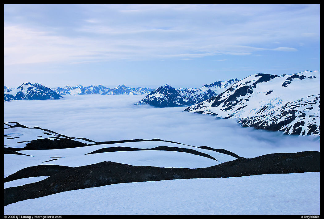 Dark bands of freshly uncovered terrain, snow, and low clouds, dusk. Kenai Fjords  National Park, Alaska, USA.