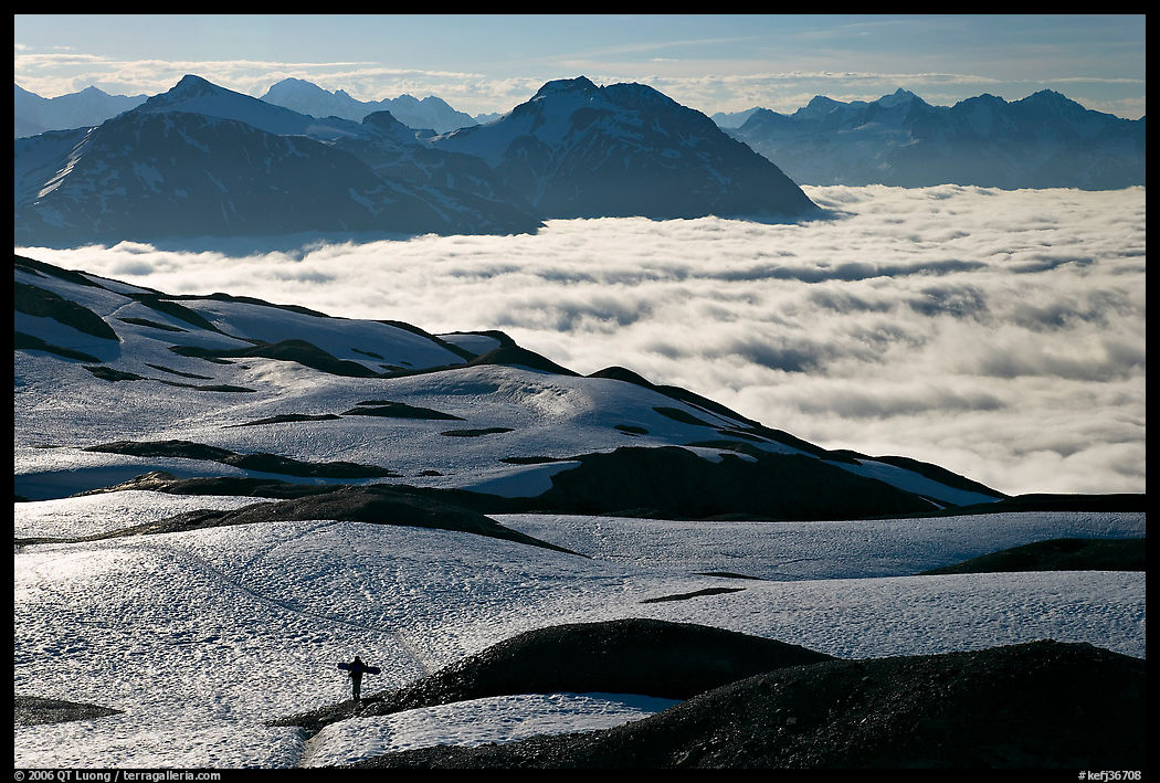Mountains with snowboarder hiking down on snow-covered trail. Kenai Fjords  National Park, Alaska, USA.