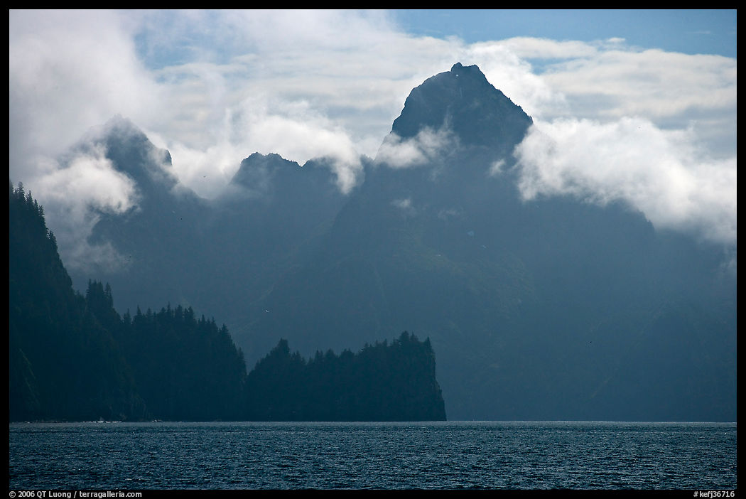 Peak emerging from the fog above bay waters. Kenai Fjords  National Park, Alaska, USA.