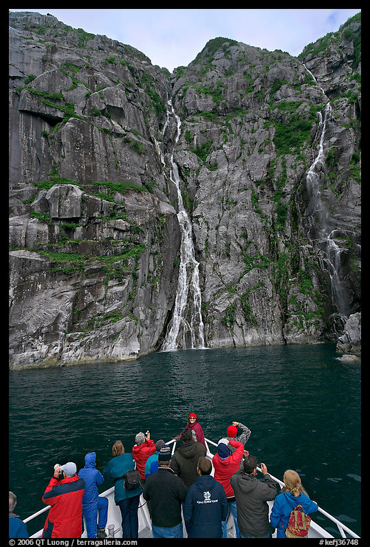 Passengers looking at waterfalls from  bow of tour boat, Cataract Cove. Kenai Fjords  National Park, Alaska, USA.
