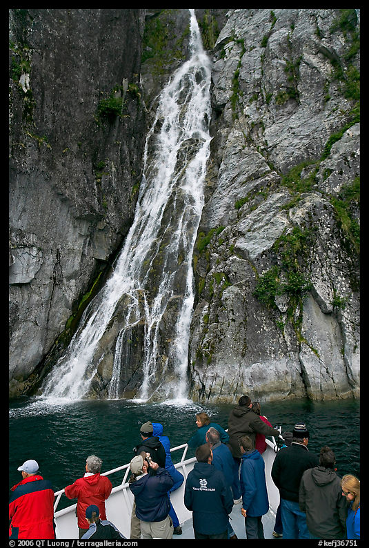 Passengers look at waterfall from tour boat, Cataract Cove, Northwestern Fjord. Kenai Fjords  National Park, Alaska, USA.