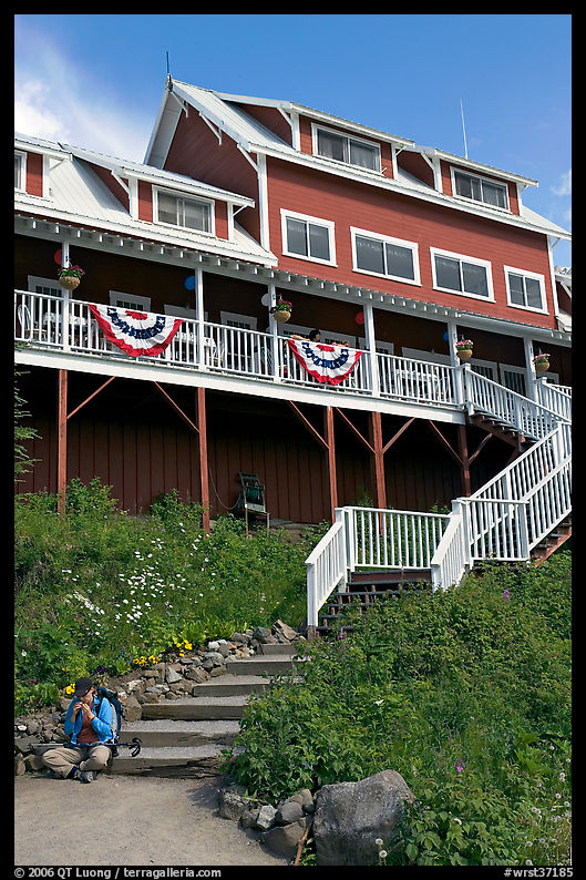 Hiker sitting on steps of Kennicott Lodge. Wrangell-St Elias National Park, Alaska, USA.