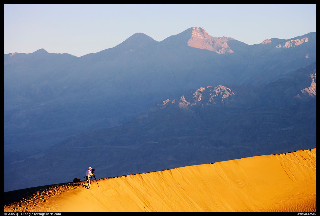 Photographer on dune ridge at sunrise. Death Valley National Park, California, USA.