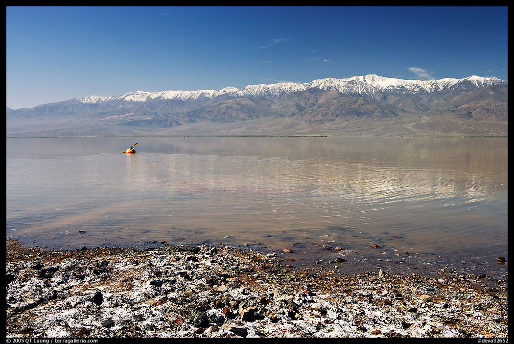 Salt formations, kayaker in a distance, and Panamint range. Death Valley National Park, California, USA.