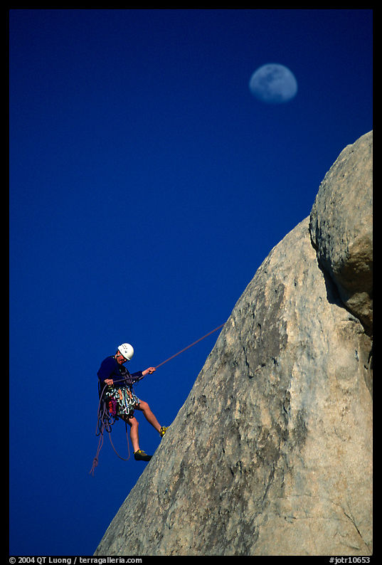 Climber rappelling down with moon. Joshua Tree  National Park, California, USA.