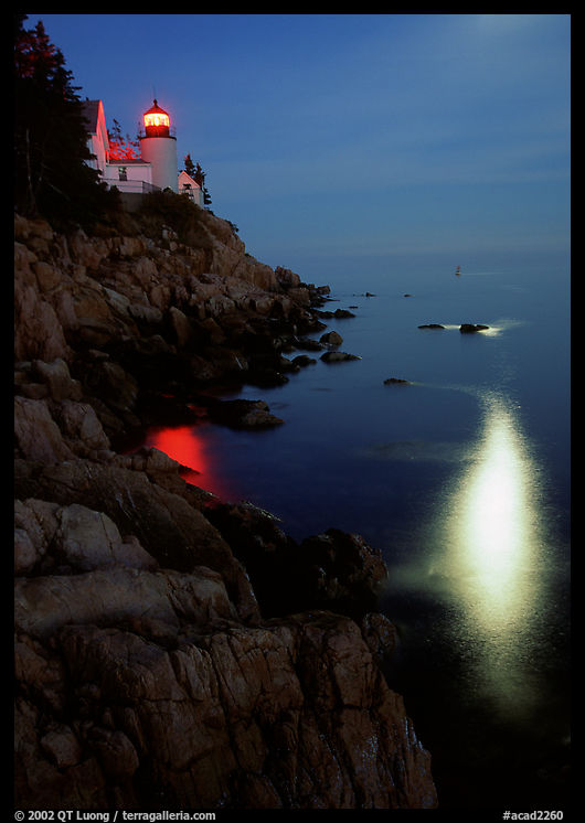 Bass Harbor lighthouse by night with reflections of moon and lighthouse light. Acadia National Park, Maine, USA.