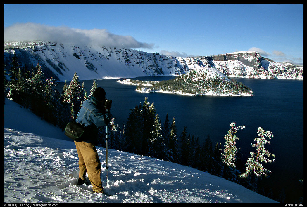 Photographer on  rim of  Lake in winter. Crater Lake National Park, Oregon, USA.