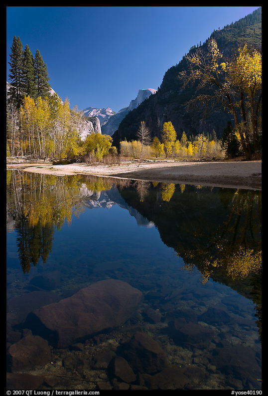 Rocks and Merced River reflexions of trees and Half-DOme. Yosemite National Park, California, USA.