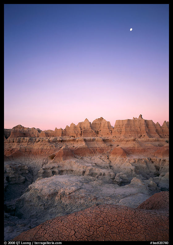 Mud cracks, badlands, and moon at dawn. Badlands National Park, South Dakota, USA.