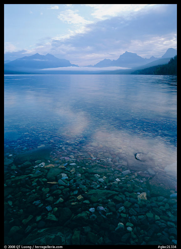 Pebbles, lake Mc Donald, and foggy mountain range, early morning. Glacier National Park, Montana, USA.