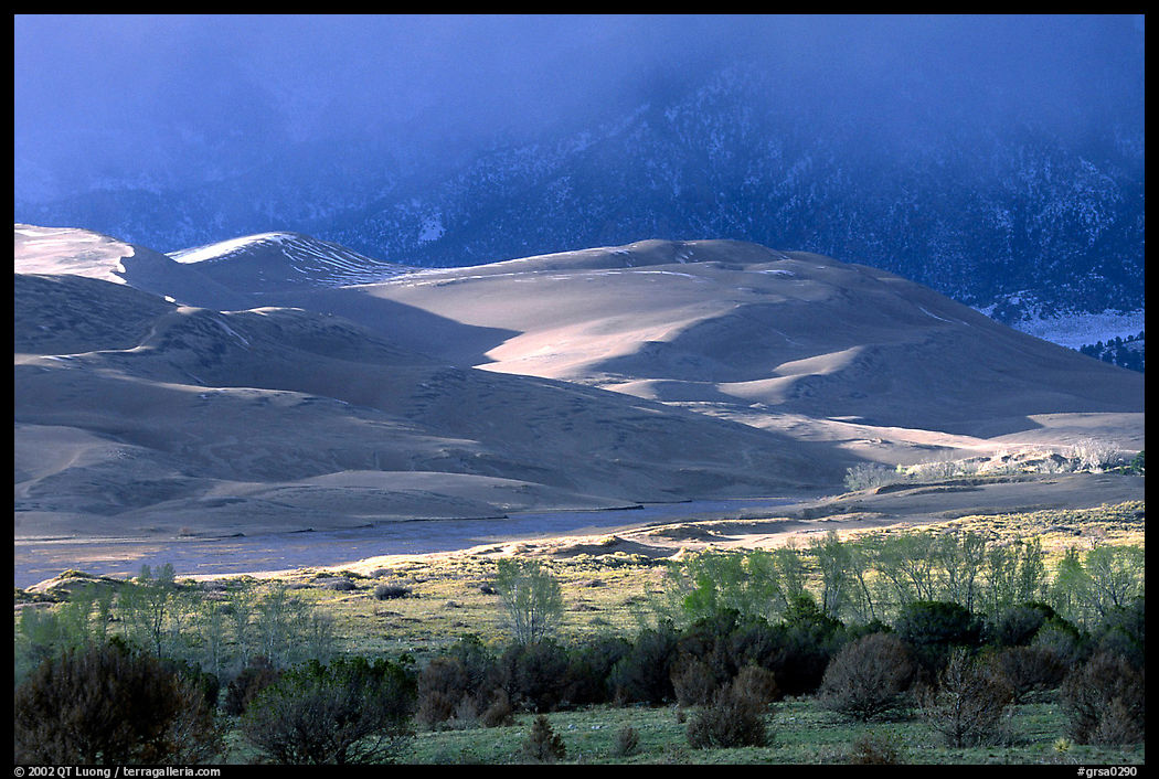 Storm light illuminates portions of the dune field. Great Sand Dunes National Park, Colorado, USA.
