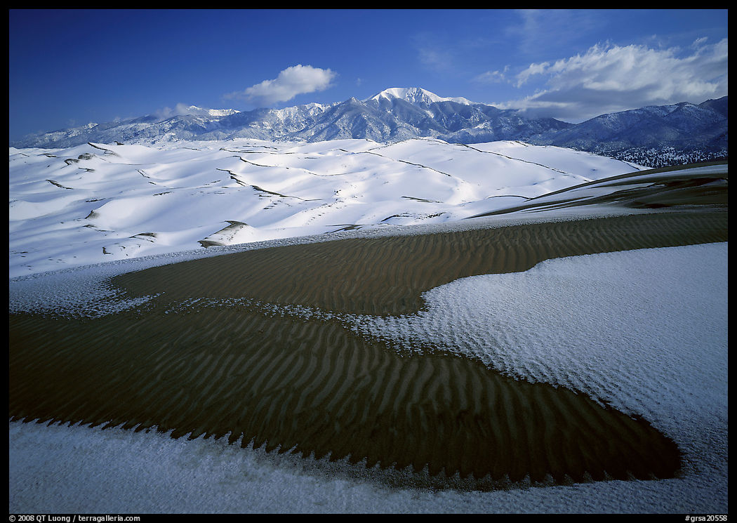 Patch of sand, snow-covered dunes, Sangre de Christo mountains. Great Sand Dunes National Park, Colorado, USA.