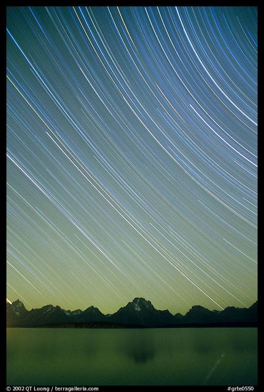 Star trails on Teton range above Jackson lake, dusk. Grand Teton National Park, Wyoming, USA.