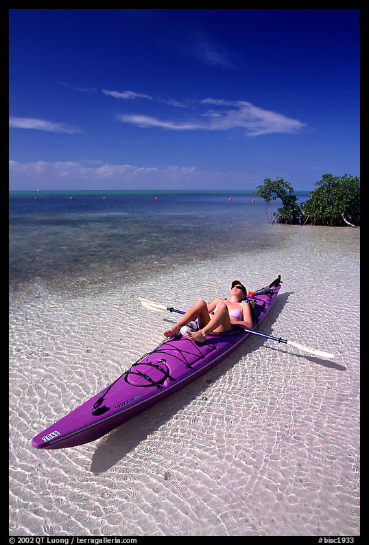 Woman sunning herself on sea kayak parked on shore,  Elliott Key. Biscayne National Park, Florida, USA.