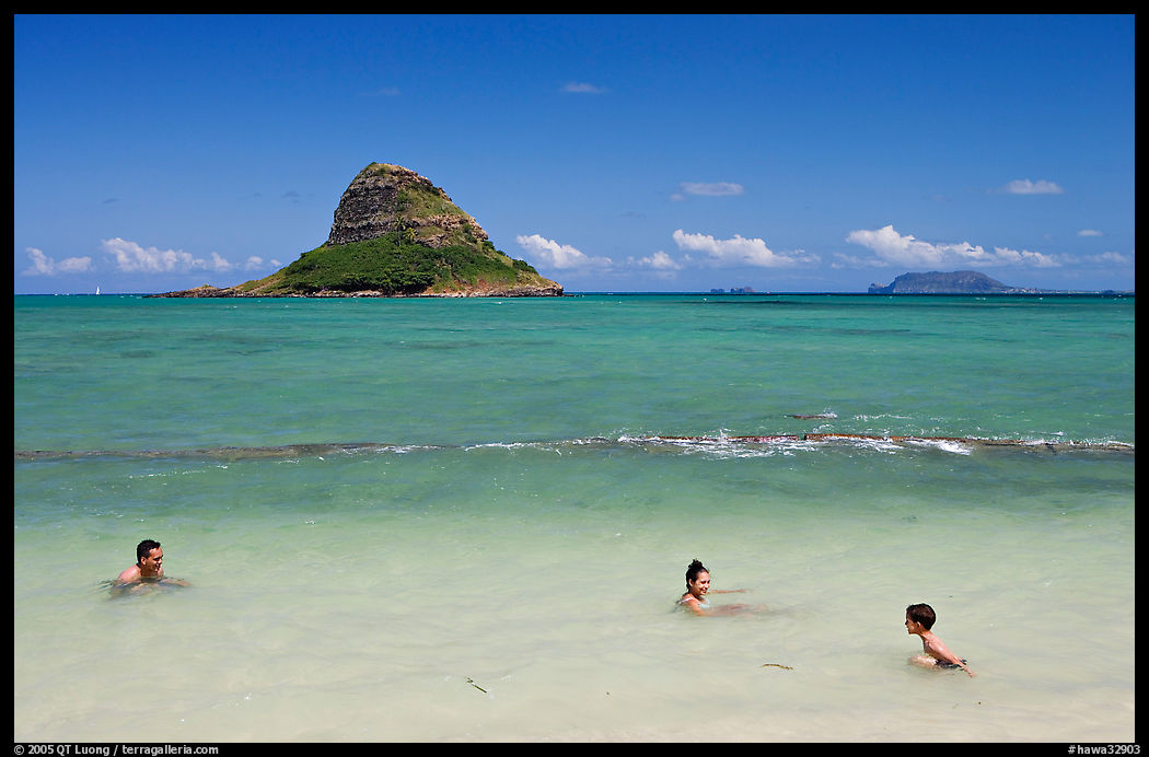 Family in the waters of Kualoa Park with Chinaman's Hat in the background. Oahu island, Hawaii, USA