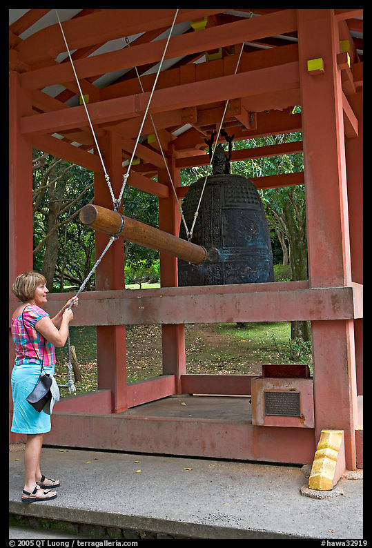 Visitor rings the sacred bell before entering Byodo-In temple. Oahu island, Hawaii, USA