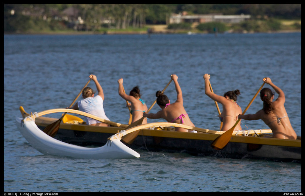Back view of women in bikini paddling a outrigger canoe, Maunalua Bay, late afternoon. Oahu island, Hawaii, USA