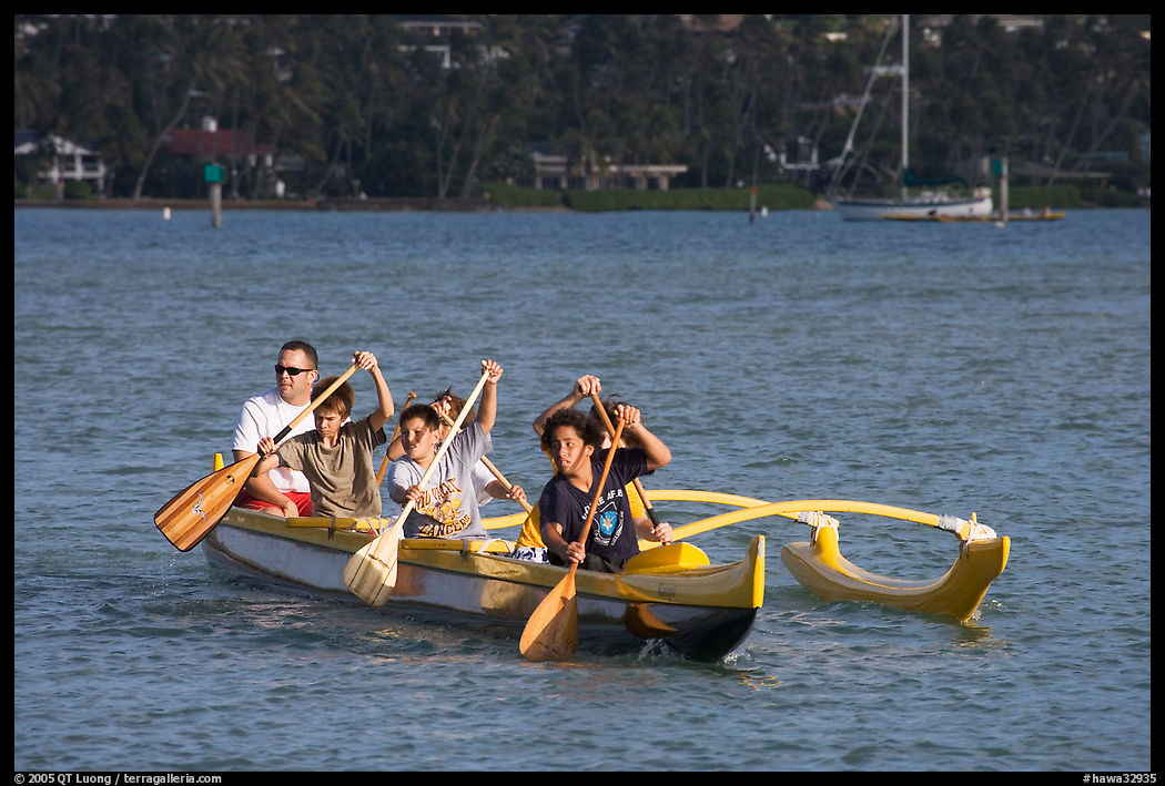 Boys paddling an outrigger canoe, Maunalua Bay, late afternoon. Oahu island, Hawaii, USA