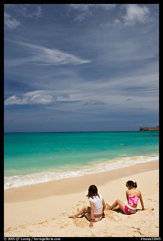 Young women sitting on Waimanalo Beach. Oahu island, Hawaii, USA