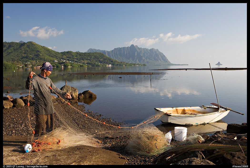 Fisherman pulling out net out of small baot, Kaneohe Bay, morning. Oahu island, Hawaii, USA