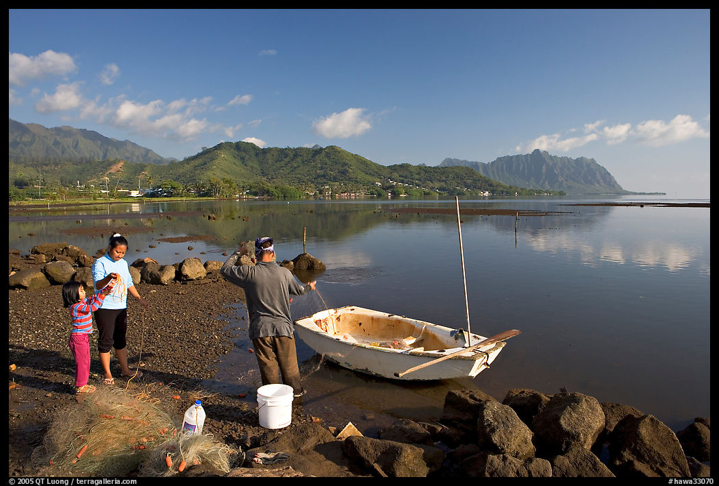 Fisherman and family pulling out net out of small baot, Kaneohe Bay, morning. Oahu island, Hawaii, USA