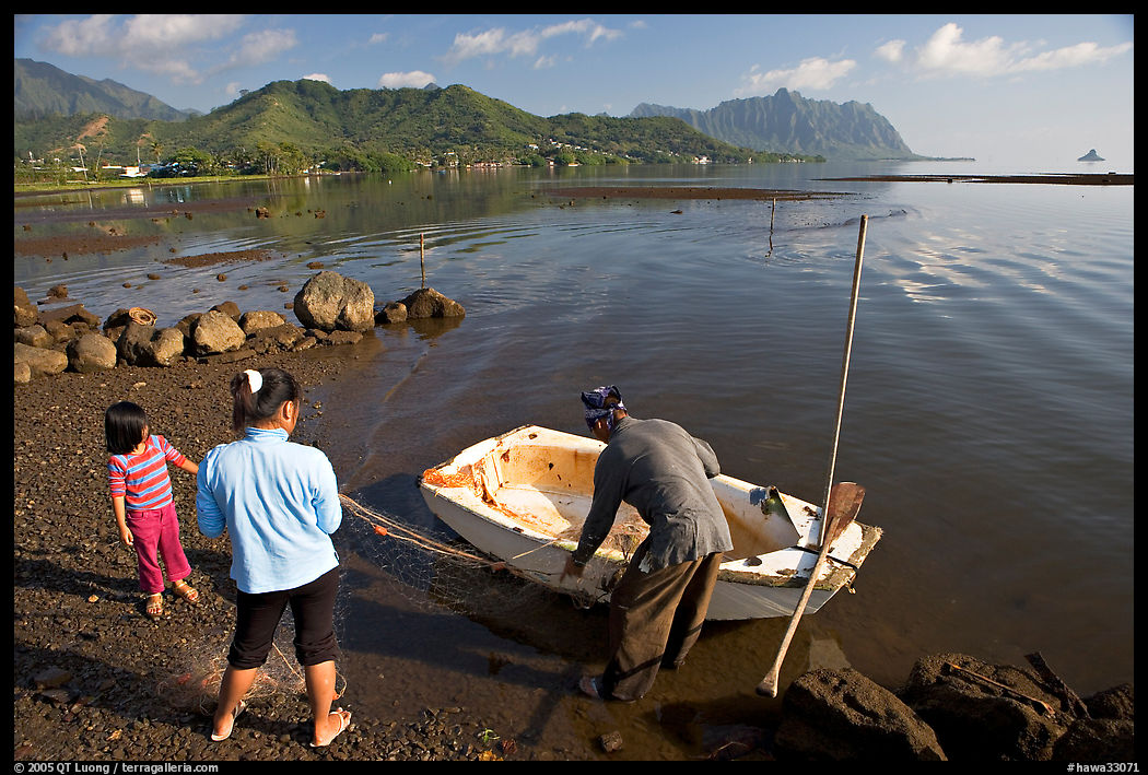Fisherman and family pulling out net out of small baot, Kaneohe Bay, morning. Oahu island, Hawaii, USA