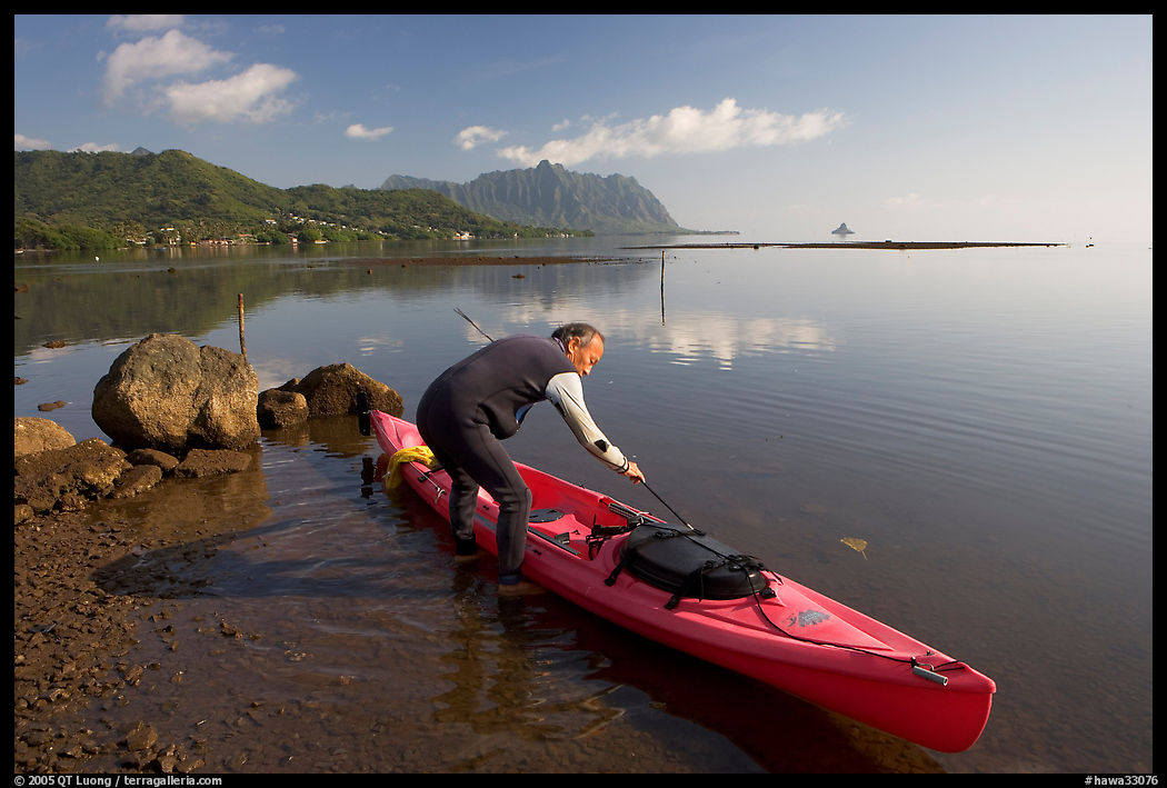 Man loading sea kayak for a fishing trip, Kaneohe Bay, morning. Oahu island, Hawaii, USA