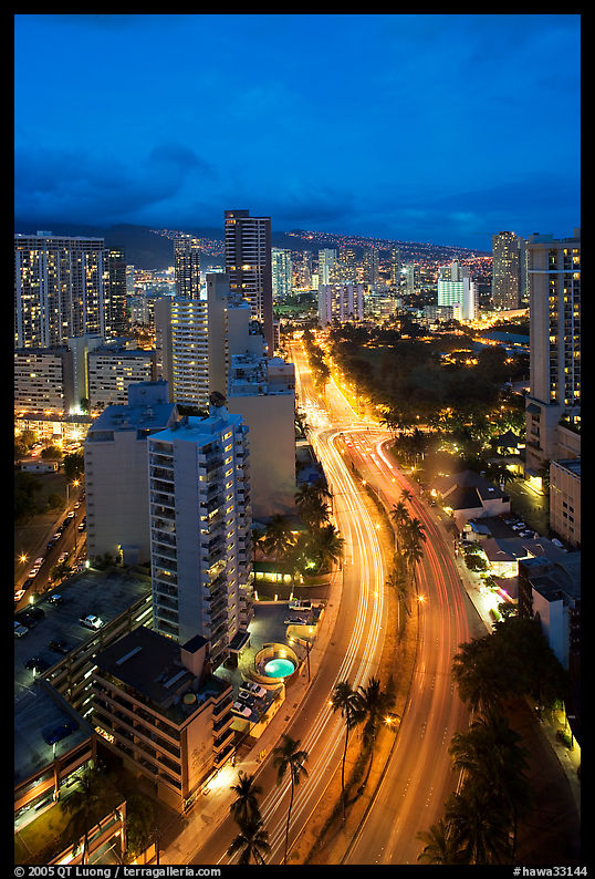 Boulevard and high rise buildings at dusk. Waikiki, Honolulu, Oahu island, Hawaii, USA
