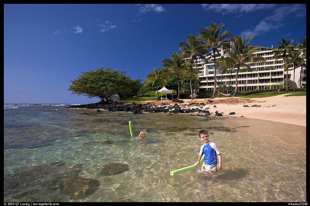 Children on Puu Poa Beach and Princeville Hotel. North shore, Kauai island, Hawaii, USA