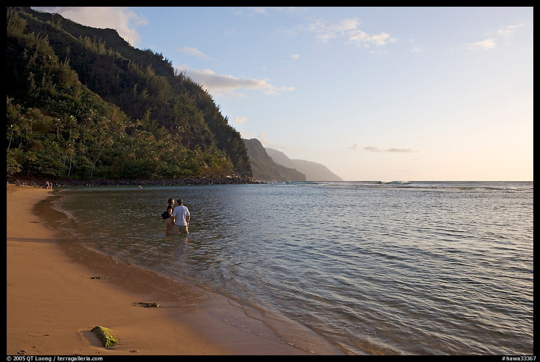 Couple standing in water looking at the Na Pali Coast, Kee Beach, late afternoon. Kauai island, Hawaii, USA