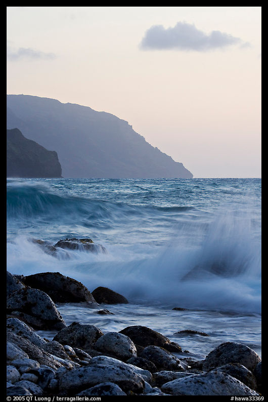 Boulders, waves, and Na Pali cliffs, sunset. Kauai island, Hawaii, USA