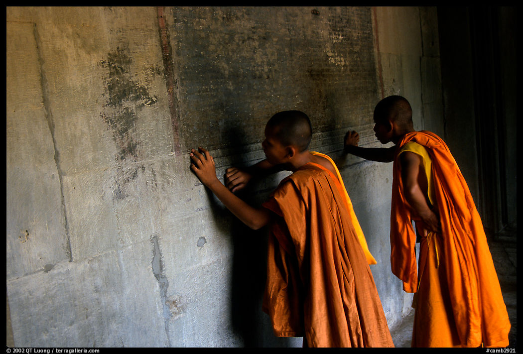 Two buddhist monks examine the bas-reliefs in Angkor Wat, the longest in the world. Angkor, Cambodia