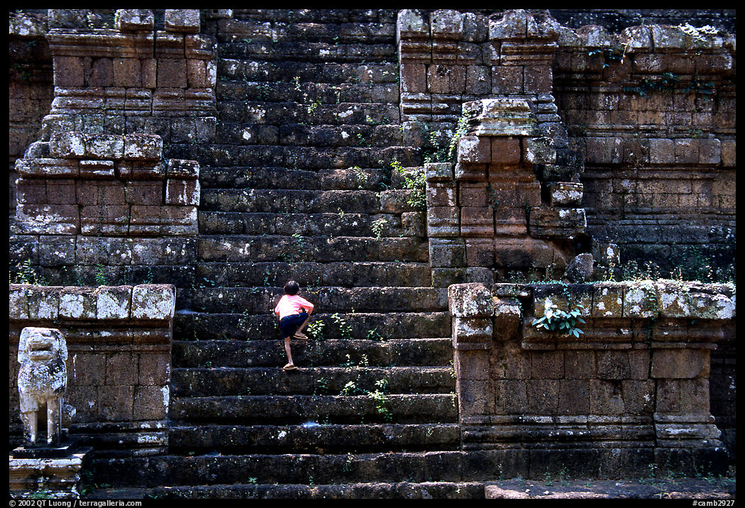 Boy climbs near-vertical staircase, Angkor Thom complex. Angkor, Cambodia