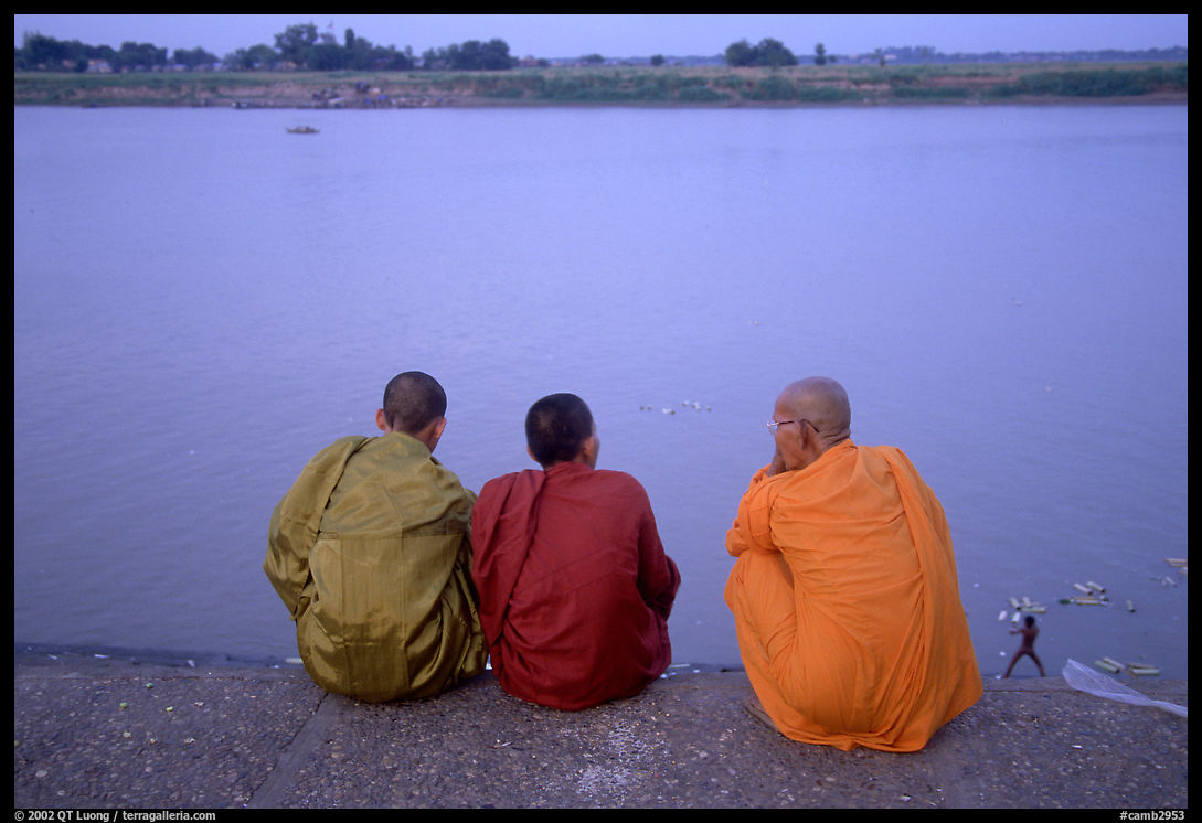 Buddhist monks sit on the banks of the Tongle Sap river at dusk. Cambodia